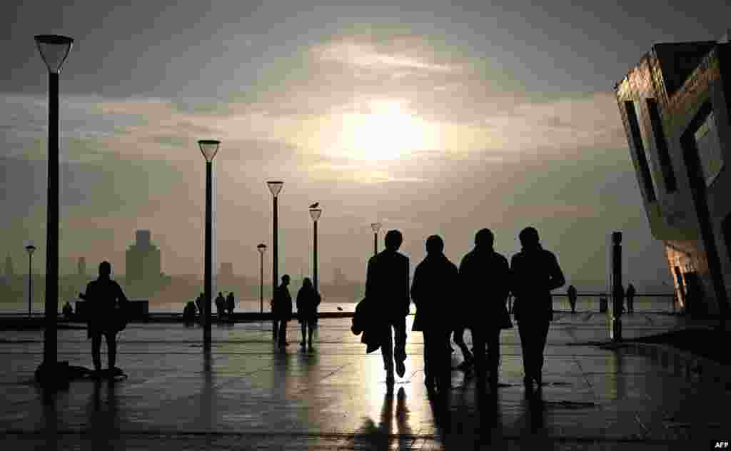 The Beatles Statue, created by sculptor Andy Edwards is seen against the setting sun on the Pier Head in Liverpool in northwest England.