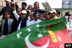 Mantan Perdana Menteri Pakistan Imran Khan (4L) memberi isyarat kepada para pendukungnya selama pawai anti-pemerintah menuju kota Islamabad, menuntut pemilihan awal, di distrik Muridke, sekitar 29 km dari Lahore, 30 Oktober 2022. (Arif ALI / AFP)