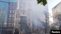 Firefighters help a local woman evacuate from a residential building destroyed by a Russian drone strike, which local authorities consider to be Iranian-made unmanned aerial vehicles (UAVs) Shahed-136, in Kyiv, Oct. 17, 2022.