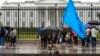 FILE - A member of the District of Columbia's Uyghur community sits in the rain as the East Turkistan Awakening Movement rallies outside the White House against the Chinese Communist Party, in Washington, Oct. 1, 2022. 