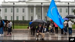 FILE - A member of the District of Columbia's Uyghur community sits in the rain as the East Turkistan Awakening Movement rallies outside the White House against the Chinese Communist Party, in Washington, Oct. 1, 2022. 