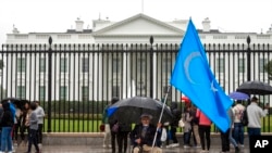 A member of the District of Columbia's Uyghur community sits in the rain as the East Turkistan Awakening Movement holds a rally outside the White House against the Chinese Communist Party (CCP) to coincide with the 73rd National Day of the People's Republ