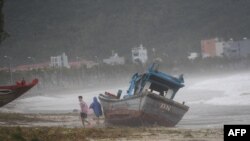 Anak-anak bermain di samping perahu yang terdampar setelah topan Noru menghantam Danang, 28 September 2022. (Nhac NGUYEN / AFP)