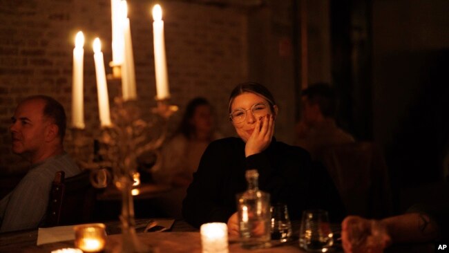 A woman waits for her dinner to arrive as she sits at a table with a candelabra at Brasserie Surrealiste in Brussels, Sept. 28, 2022.