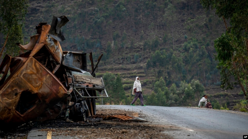 FILE - A man crosses the road near a destroyed truck in the Tigray region of northern Ethiopia, May 11, 2021. 