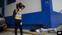 El periodista haitiano Romelo Vilsaint, quien falleció tras ser baleado, yace boca abajo en el estacionamiento de un departamento policial de Puerto Príncipe, Haití, el domingo 30 de octubre de 2022. (AP Foto)