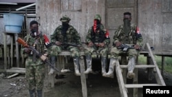 ARCHIVO - Rebeldes del Ejército de Liberación Nacional colombiano descansan afuera de una casa cerca del río San Juan, Colombia, en agosto de 2017.