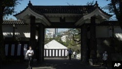 People go through a gate as they walk toward the building to be used for the state funeral of former Prime Minister Shinzo Abe as authorities have deployed extra officers to beef up securities in Tokyo, Sept. 26, 2022.