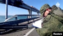 Слідчий РФ інспектує пошкодження Кримського мосту. 8 жовтня 2022 року. Фото надане Reuters з іншого джерела