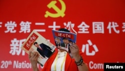 资料照：一名记者在北京一家酒店的中共二十大新闻中心阅读有着中国领导人习近平照片封面的杂志。（2022年10月19日）