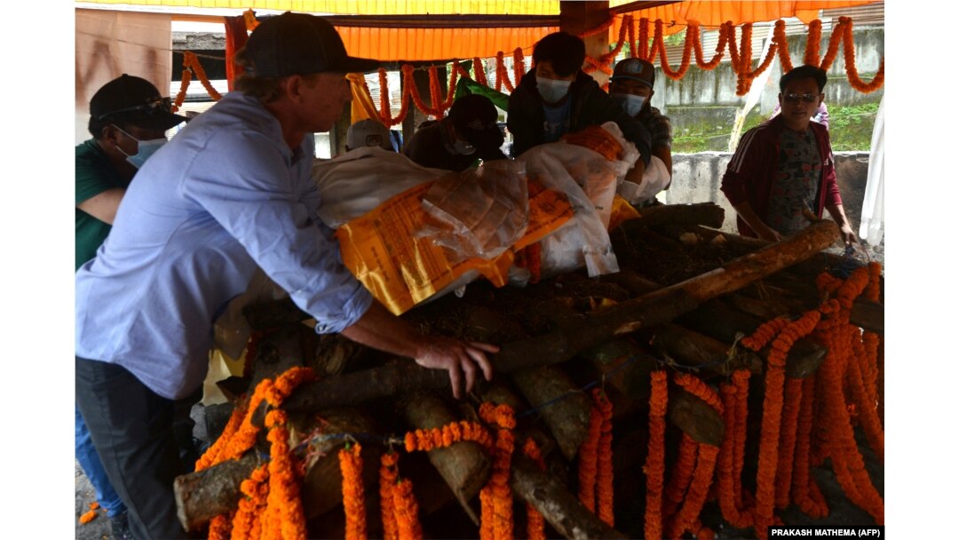 Jim Morrison (kiri), mitra pendaki gunung ski AS Hilaree Nelson, mengangkat jenazah Nelson ke atas tumpukan kayu pemakaman sebelum dikremasi di Kathmandu pada 2 Oktober 2022. (Foto: PRAKASH MATHEMA/AFP)