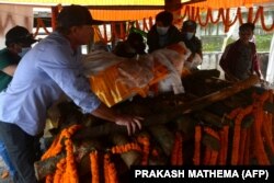 Jim Morrison (kiri), mitra pendaki gunung ski AS Hilaree Nelson, mengangkat jenazah Nelson ke atas tumpukan kayu pemakaman sebelum dikremasi di Kathmandu pada 2 Oktober 2022. (Foto: PRAKASH MATHEMA/AFP)