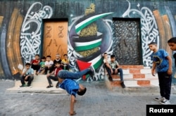 A Palestinian boy performs breakdancing on the street in Nusseirat refugee camp in central Gaza Strip, October 14, 2022. (REUTERS/Ibraheem Abu Mustafa)