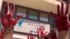 This image grab from a UGC video made available on Twitter on Oct. 9, 2022, shows Iranian students from the Faculty of Arts at Tehran's Azad University participating in a protest with their palms covered in red paint to symbolize blood. (Photo by UGC/AFP)