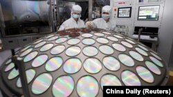 FILE - Employees work on the semiconductor chip production line of Jiangsu Azure Corp in Huaian, Jiangsu province, China, March 25, 2022.