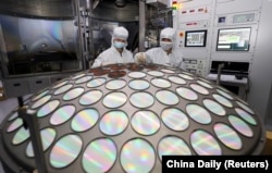 FILE - Employees work on the semiconductor chip production line of Jiangsu Azure Corp in Huaian, Jiangsu province, China, March 25, 2022.