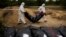 FILE - Members of a forensic team carry a plastic bag with a body inside as they exhume a mass grave in Lyman, Ukraine, Oct. 11, 2022. 
