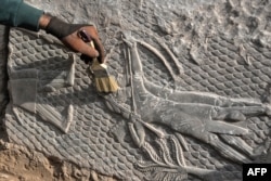 An Iraqi worker excavates a rock-carving relief recently found at the Mashki Gate, one of the monumental gates to the ancient Assyrian city of Nineveh, on the outskirts of what is today the northern Iraqi city of Mosul, Oct. 19, 2022.