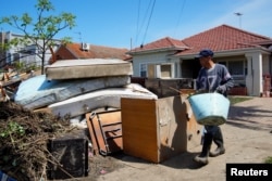 Local resident Van Tran cleans up outside his damaged home following severe flooding in the Maribyrnong suburb of Melbourne, Oct. 17, 2022.
