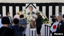 Sejumlah pelayat menaruh karangan bunga di altar di luar area Balai Nippon Budokan, yang menjadi tempat acara pemakaman kenegaraan bagi mantan Perdana Menteri Jepang Shinzo Abe, di Tokyo, pada 27 September 2022. (Foto: Reuters/Issei Kato)