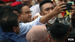 Anies Baswedan (tengah) melakukan swafoto dengan pendukungnya setelah dirinya resmi menyelesaikan tugasnya selama 5 tahun dari 2017 hingga 2022 sebagai gubernur DKI Jakarta pada 16 Oktober tahun ini. (VOA/Indra Yoga)