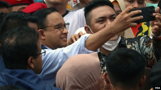 Anies Baswedan (tengah) melakukan swafoto dengan pendukungnya setelah dirinya resmi menyelesaikan tugasnya selama 5 tahun dari 2017 hingga 2022 sebagai gubernur DKI Jakarta pada 16 Oktober tahun ini. (VOA/Indra Yoga)