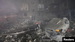 A rescuer works at a site of a residential building heavily damaged by a Russian missile strike in Zaporizhzhia, Ukraine, Oct. 10, 2022.