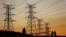 FILE - Locals walk past electricity pylons in Soweto, South Africa, July 3, 2022.