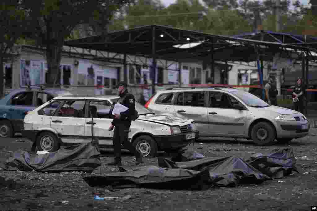 Seorang petugas polisi Ukraina berjalan melewati kantung-kantung berisi mayat orang-orang yang tewas setelah serangan Rusia di kota Zaporizhzhia, Ukraina (30/9).