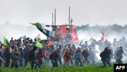 Activists walk among tear gas following clashes with riot mobile gendarmes during a demonstration against the "basins" near the construction site of a new water reserve for agricultural irrigation, in Sainte-Soline, western France, on Oct. 29, 2022.