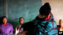 A woman covered with a blanket casts her vote at a poling station in Maseru, Lesotho, Oct. 7, 2022. 