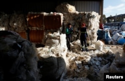 Antonella and Natalia, who work as garbage recyclers, have a laugh as they work with plastic and cardboard meant to be recycled, in Lomas de Zamora, in the outskirts of Buenos Aires, Argentina July 8, 2022. (REUTERS/Agustin Marcarian)