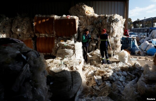 Antonella and Natalia, who work as garbage recyclers, have a laugh as they work with plastic and cardboard meant to be recycled, in Lomas de Zamora, in the outskirts of Buenos Aires, Argentina July 8, 2022. (REUTERS/Agustin Marcarian)