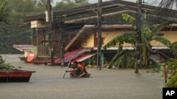 Residents paddle through floodwaters in Ubon Ratchathani province, northeastern Thailand, Monday, Oct. 3, 2022.