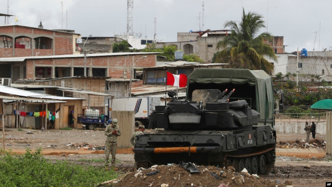 ARCHIVO - Unidades blindadas del ejército peruano están estacionadas en el lado peruano de la frontera, con la ciudad ecuatoriana de Huaquillas detrás, vista desde Tumbes, Perú, en enero de 2021.