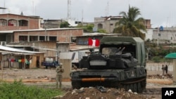 ARCHIVO - Unidades blindadas del ejército peruano están estacionadas en el lado peruano de la frontera, con la ciudad ecuatoriana de Huaquillas detrás, vista desde Tumbes, Perú, en enero de 2021.