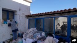 Seorang relawan mengatur sejumlah barang batuan bagi para migran yang ditempatkan di sebuah gedung sekolah tua yang dijadikan tempat penampungan sementara di pulau Kythira, Yunani, pada 7 Oktober 2022. (Foto: AP/Thanassis Stavrakis)