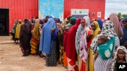 FILE - Somali women and children who left rural areas due to drought receive nutritional assistance at a camp for the internally displaced, on the outskirts of Baidoa, Somalia, Oct. 12, 2022.