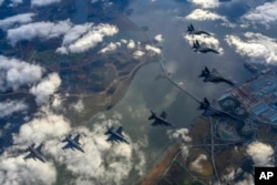 In this photo provided by South Korea Defense Ministry, South Korean Air Force's F15K fighter jets and U.S. Air Force's F-16 fighter jets, fly in formation during a joint drill in an undisclosed location in South Korea, Tuesday, Oct. 4, 2022. (South Korea Defense Ministry via AP)