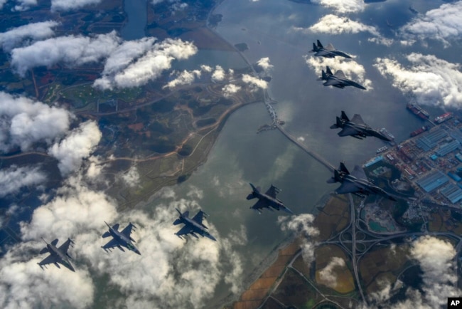 In this photo provided by South Korea Defense Ministry, South Korean Air Force's F15K fighter jets and U.S. Air Force's F-16 fighter jets, fly in formation during a joint drill in an undisclosed location in South Korea, Tuesday, Oct. 4, 2022. (South Korea Defense Ministry via AP)