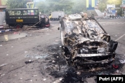 Kendaraan yang dibakar di luar stadion Kanjuruhan di Malang, Jawa Timur pada 2 Oktober 2022.. (Foto: AFP/Putri)