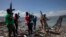 FILE - Armed men are seen near the perimeter wall that encloses the currently blockaded Terminal Varreux, in Port-au-Prince, Haiti, Oct. 6, 2021.