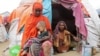 A Somali woman affected by the worsening drought due to failed rain seasons holds her daughter, 3, as her grandmother looks on, outside their makeshift shelter at the Alla Futo camp for internally displaced people, on the outskirts of Mogadishu, Somalia, Sept. 23, 2022.