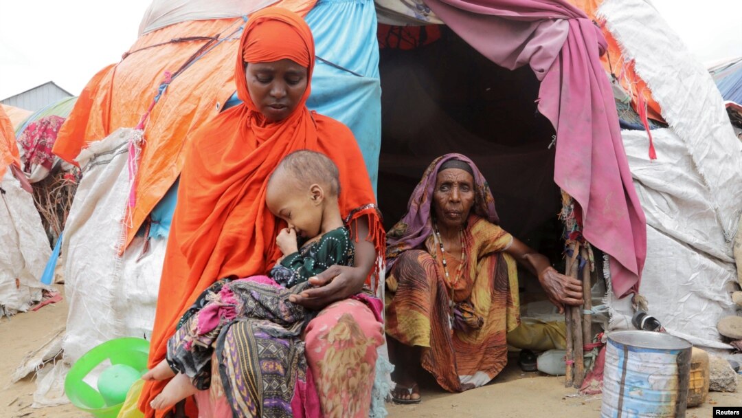 A Somali woman affected by the worsening drought due to failed rain seasons holds her daughter, 3, as her grandmother looks on, outside their makeshift shelter at the Alla Futo camp for internally displaced people, on the outskirts of Mogadishu, Somalia, Sept. 23, 2022.