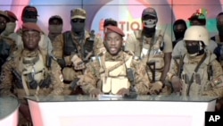 In this image from video broadcast by RTB state television, coup spokesman Capt. Kiswendsida Farouk Azaria Sorgho reads a statement in a studio in Ougadougou, Burkina Faso, on Friday evening, Sept. 30, 2022.