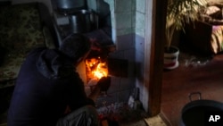 Viktor Palyanitsa lights wood in a stove in his house in Kurylivka, Ukraine, Sunday, Oct. 16, 2022. (AP Photo/Francisco Seco)
