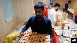 FILE - A vendor carries sweets to display for Diwali, the festival of lights, in chilbila Pratapgarh District, India, Nov. 4, 2021.