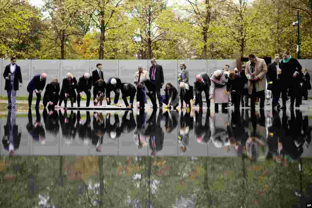 German President Frank-Walter Steinmeier, seventh from left, and others lay down flowers at the memorial to the victims of the Sinti and Roma communities killed during the holocaust, to mark the 10th anniversary of the inauguration of the memorial in Berlin.