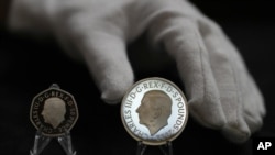 Dos monedas nuevas muestran el retrato oficial del rey Carlos III: una de 50 peniques a la izquierda y una de 5 libras a la derecha, en Londres, el jueves 29 de septiembre de 2022. (AP Foto/Alastair Grant)