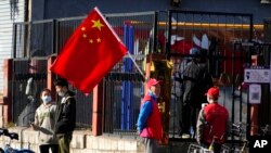 Residents and neighborhood watch members stand near a Chinese flag along a street ahead of the closing ceremony of the 20th National Congress of China's ruling Communist Party in Beijing, Oct. 22, 2022.